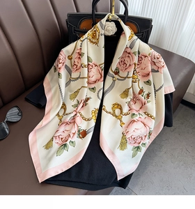 Détail d'un foulard en soie de luxe avec roses roses et chaînes dorées sur un sac chic