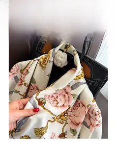 Détail du foulard en soie à motif camélia montrant le tissage sergé sur un sac à main