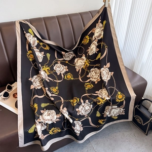 Détail d'un foulard en soie camélia sur un canapé montrant la texture brillante