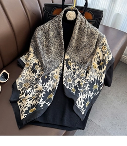 Detail of silk scarf showing floral print and smooth texture over a black sweater