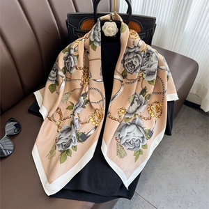 Gros plan d'un foulard en soie à motif camélia et chaîne sur un sac à main de luxe