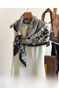 Detail of a large silk scarf featuring black and white floral prints and geometric patterns