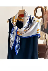 Détail d'un foulard en soie à fleurs noué, aux élégants motifs crème et bleus sur une tenue