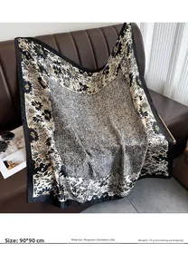 Detail of 90x90cm floral satin square scarf draped over a leather sofa in a home setting
