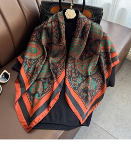Macro detail of silk scarf featuring classic orange and green paisley patterns on a bag