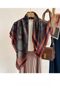 Detail of silk scarf with red and green paisley pattern styled on a white sweater