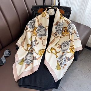 Élégant foulard en soie camélia avec chaîne dorée et motif floral sur fond blanc