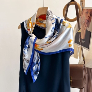 Carré en soie imprimé floral français en bleu et orange suspendu sur un haut bleu