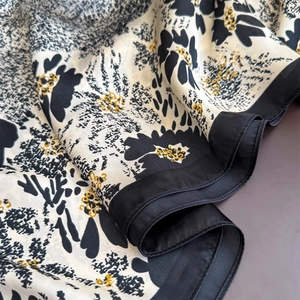 Elegant black and white floral silk scarf with vibrant yellow accents and smooth texture