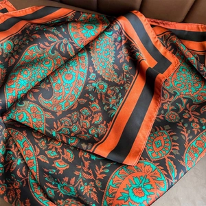 Orange and blue paisley silk shawl with vintage floral patterns on leather background