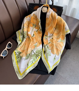 Détail d'un grand foulard en satin de soie avec des roses orange sur fond blanc cassé