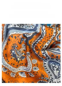 Macro shot of vibrant paisley pattern on orange satin silk square scarf texture