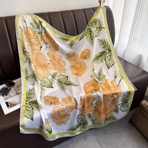 Carré de soie satiné avec motifs de roses oranges sur un canapé en cuir chic