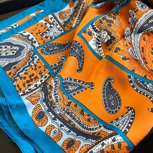 Detailed close-up of paisley pattern silk scarf with hand-rolled edges and vibrant texture