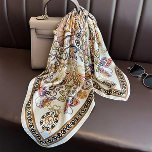 Close-up of silk-feel square scarf with paisley print hanging on a classic handbag
