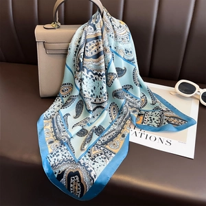 Classic paisley print blue satin scarf draped over a handbag for casual styling