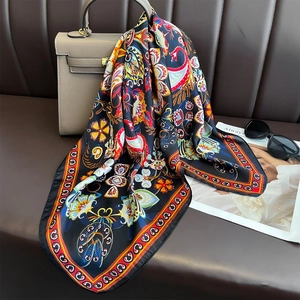 Floral paisley print square silk scarf draped over a grey leather handbag handle