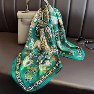 Retro paisley satin neck scarf in green and orange styled on a luxury handbag
