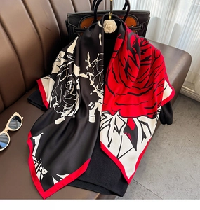 Close-up of a large satin scarf with red rose pattern and glossy silk-like texture