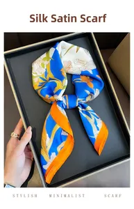Close-up of silk-like satin square scarf with orange floral prints and a royal blue border