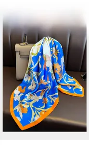 Detail of silk-feel scarf draped on a bag showing floral print and orange edges