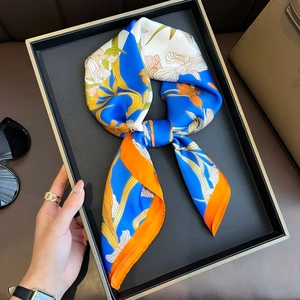 Detailed view of floral silk scarf in vibrant blue and orange pattern on a display tray