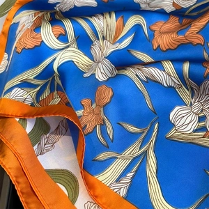 Close-up of silk floral scarf showing satin texture and hand-rolled orange edges
