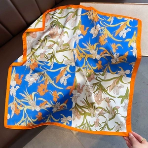 70cm silk square scarf featuring blue floral patterns and orange border on leather sofa