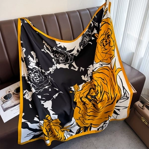 Detail of silk-like floral scarf draped on leather sofa with fashionable accessories