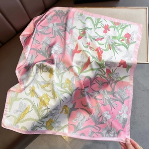 Detail view of large silk scarf featuring colorful floral print and elegant pink border