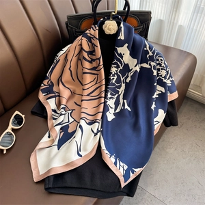 Fashionable floral silk scarf for women in navy and beige draped over a leather sofa