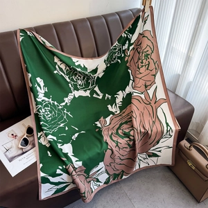 Close-up of floral silk scarf with green and pink abstract rose prints on leather sofa
