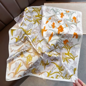 Close-up of elegant floral silk scarf with yellow iris print and delicate rolled edges