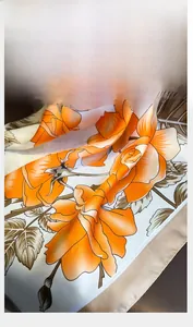 Macro shot of silk-like floral scarf detail with orange rose print and hemmed edges
