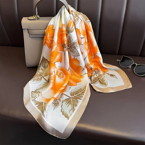 Close-up of floral silk scarf with orange roses tied to a grey leather handbag