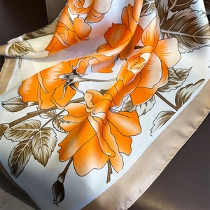 Close-up of elegant floral silk scarf showing soft texture and orange rose print