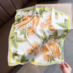 Close-up of orange floral silk scarf with yellow border on leather sofa background