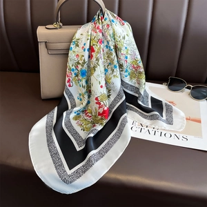 Elegant floral silk square scarf with contrast border draped over a handbag in lifestyle set