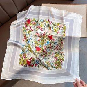 Detailed macro view of a silk scarf with colorful floral patterns and grey border