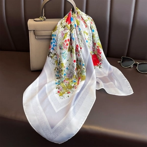 Elegant white silk square scarf with colorful floral print draped over a luxury handbag