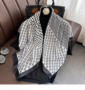 Detail of black and white houndstooth scarf with elegant chain patterns and floral brooch