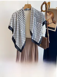 Detailed view of black and white houndstooth twill silk scarf draped on a knit sweater