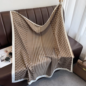 Detail of classic houndstooth silk scarf draped elegantly over a leather couch