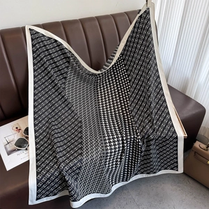 Detailed close-up of a large black and white houndstooth silk scarf on a brown sofa