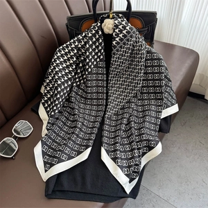 Classic houndstooth and geometric chain print silk scarf draped over a black handbag