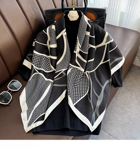 Detail of elegant black and white silk scarf with geometric patterns on a mannequin
