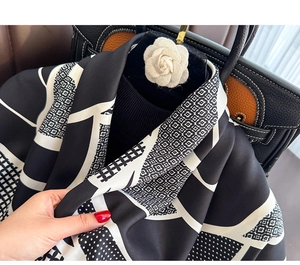 Detailed texture of black and white printed silk scarf with elegant geometric patterns