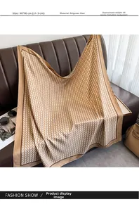Detail of 90x90cm satin scarf with V-letter pattern draped over a leather sofa