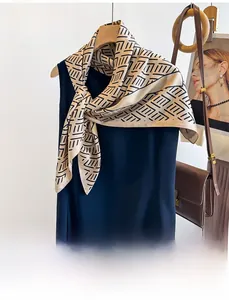 Detail of silk twill scarf with black geometric lines tied on a navy dress neckline
