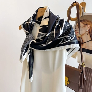 Detailed view of black and white geometric silk scarf tied on a white sleeveless dress